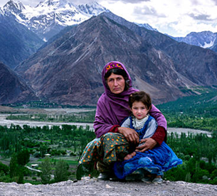 Local family in traditional clothing with Karakoram mountains in Hunza Valley Pakistan tour