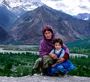 Local family in traditional clothing with Karakoram mountains in Hunza Valley Pakistan tour