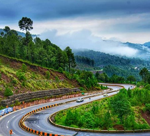 Winding mountain road surrounded by pine forests in Murree Hills travel package
